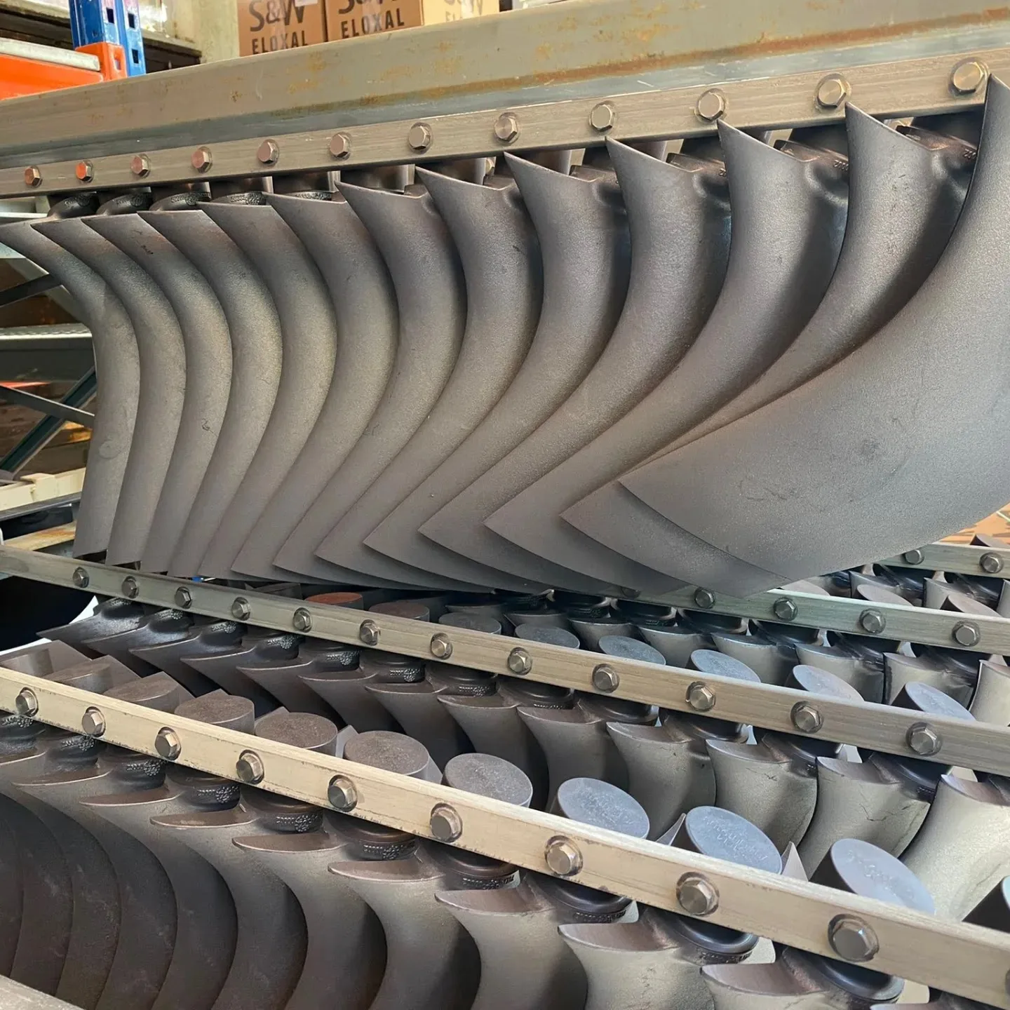 Gebogene Aluminiumteile in langer Reihe auf einem Gestell