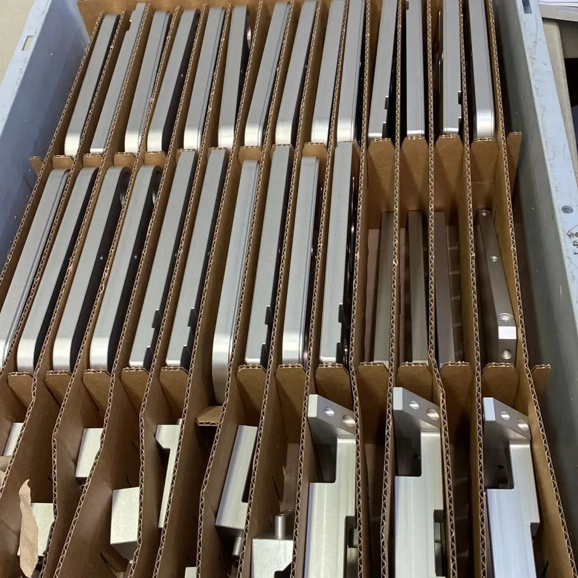 Eloxierte Aluminiumprofile stehen sortiert in einem Karton mit Trennstegen
