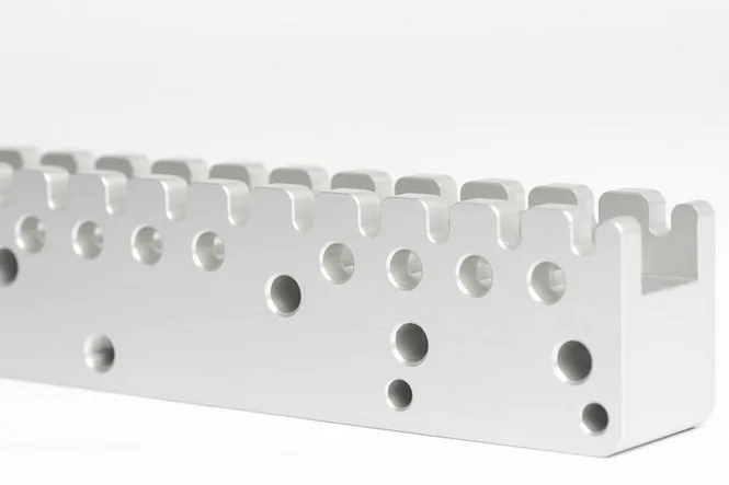 Natur eloxierte Aluminiumleiste mit Bohrungen und Aussparungen vor weißem Hintergrund