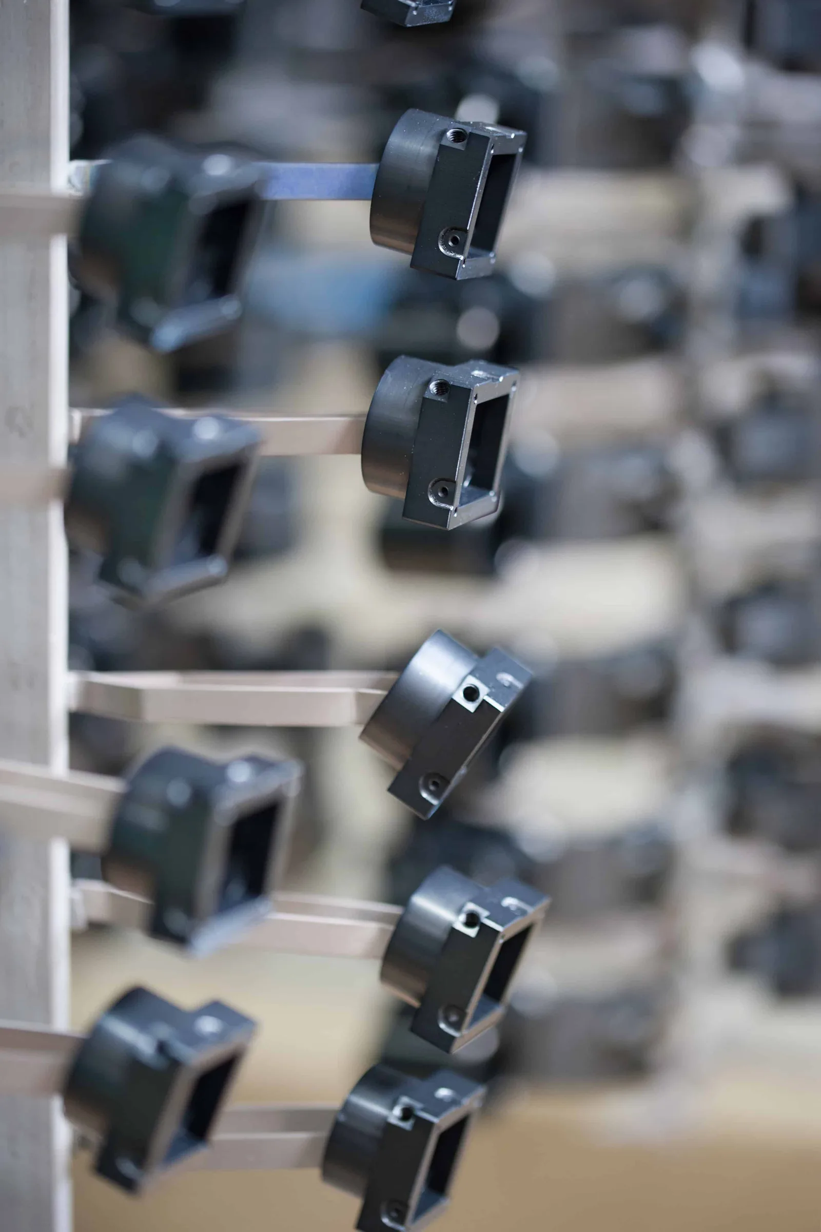 Schwarz eloxierte Aluminiumteile hängen an einem Gestell